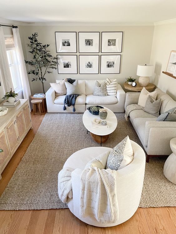 a neutral small living room with a cane TV unit, neutral sofas, a chair, a coffee table, a gallery wall and some decor and plants