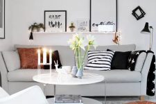 a small Scandinavian living room done in neutrals, with touches of black, printed pillows and string lights and lamps