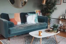 a small living room with a green accent wall, a blue sofa with printed pillows, a printed rug, a coffee table, a bar cart and greenery