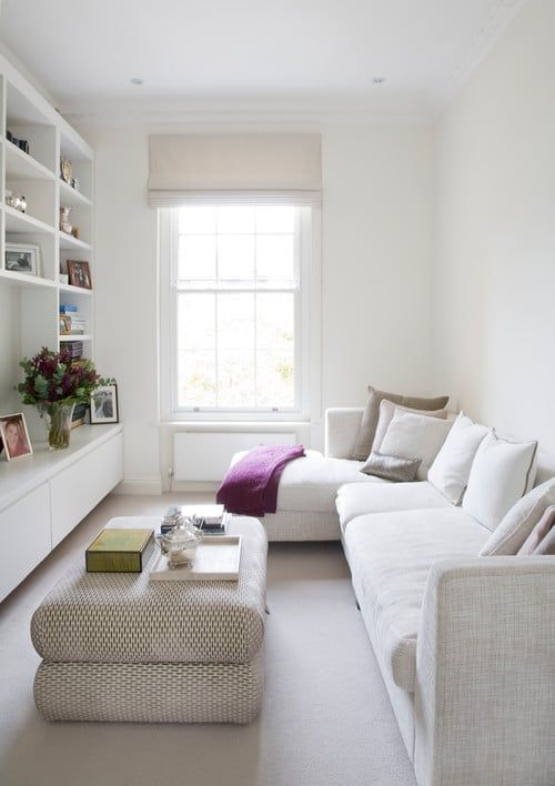 a small neutral living room with a sectional, an ottoman, a large storage unit with various stuff is a lovely space