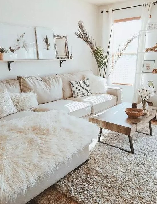 an inviting living room with a white sofa, a low coffee table, a ledge gallery wall and a potted statement plant