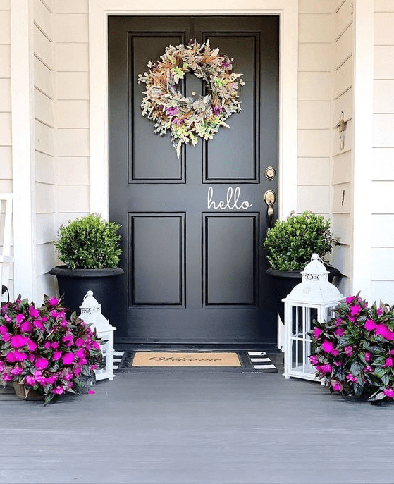 a bright spring porch done with hot pink blooms in pots, with a bright and textural floral and greenery wreath and greenery in pots