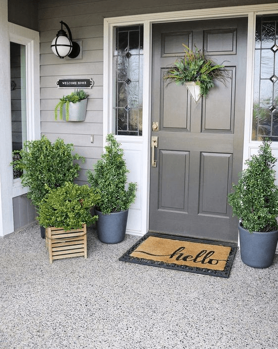 a fresh spring porch decorated only with greenery in pots and crates and with greenery on the door
