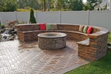 herringbone clad brick patio with a fire pit and a round bench of brick