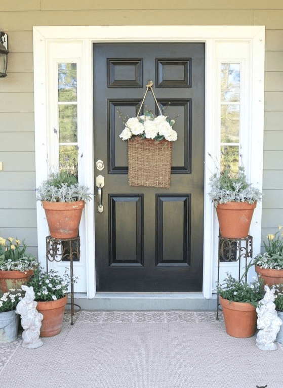 potted greenery and blooms, a basket with white flowers and some bunny statuettes for a farmhouse spring porch