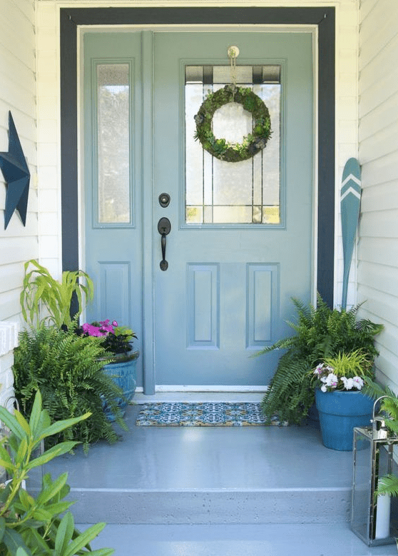 potted greenery and blooms, a greenery wreath and candle lanterns for a fresh spring porch