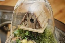 02 a cloche terrarium with faux greenery and moss, a bird house and a nest