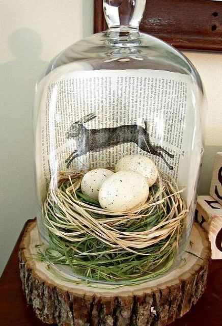 a modern terrarium with grass, hay, speckled eggs and a book page