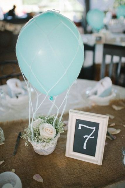 a tiny basket with baby's breath and roses and a blue balloon for a hot air balloon centerpiece