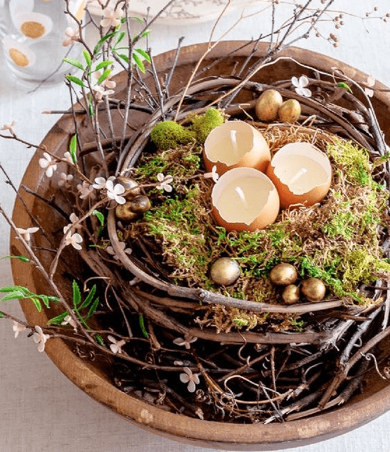 a beautiful and unusual Easter centerpiece of a bowl, vines, blooms, moss, gilded eggs and egg shell candles is wow