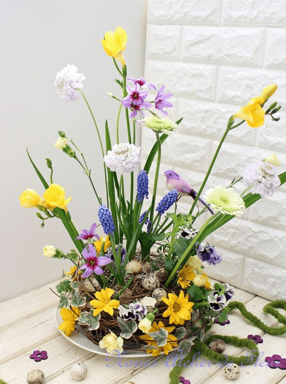 a bold Easter flower arrangement with a nest with speckled eggs, bright blooms and fake birds