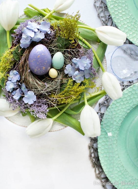a bright Easter nest with lilac and blue eggs, blue flowers nd greenery is a cool centerpiece