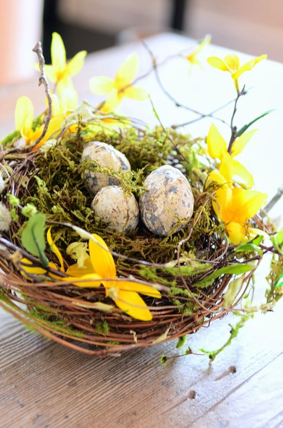 a bright spring decoration of a nest with greenery and yellow blooms plus speckled eggs is a cool idea for Easter
