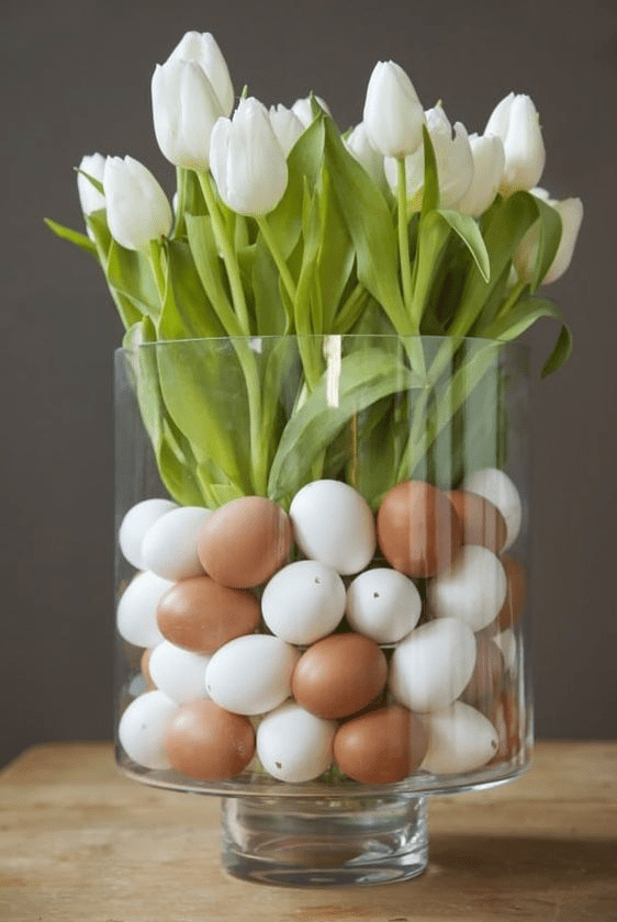 a classy modern Easter centerpiece of a clear glass with faux eggs and white tulips is a very natural and fast to make arrangement
