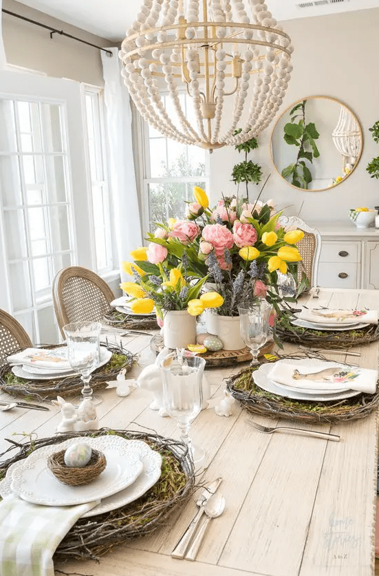 a colorful rustic Easter tablescape with vine wreaths and moss, nests with eggs, bunnies, bold blooms and greenery