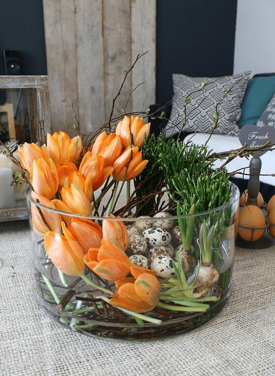 a jar with orange tulips, bulbs and speckled eggs is a bold Easter centerpiece done in modern style