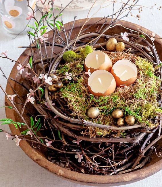 a lovely Easter centerpiece of a vine nest, moss, egg shell candles and gold eggs plus faux blooms is amazing