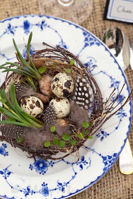 a messy Easter decoration of a nest with greenery, feathers, speckled eggs is a cool piece