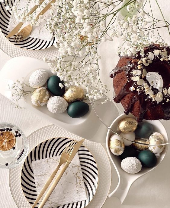 a modern Easter tablescape with baby's breath, black and white porcelain, gold cutlery, black, white and gold eggs is amazing
