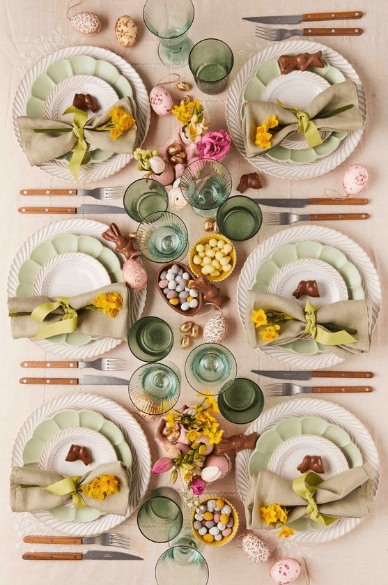 a modern pastel Easter tablescape with blush and green linens, green plates, green glasses, pastel eggs and blooms