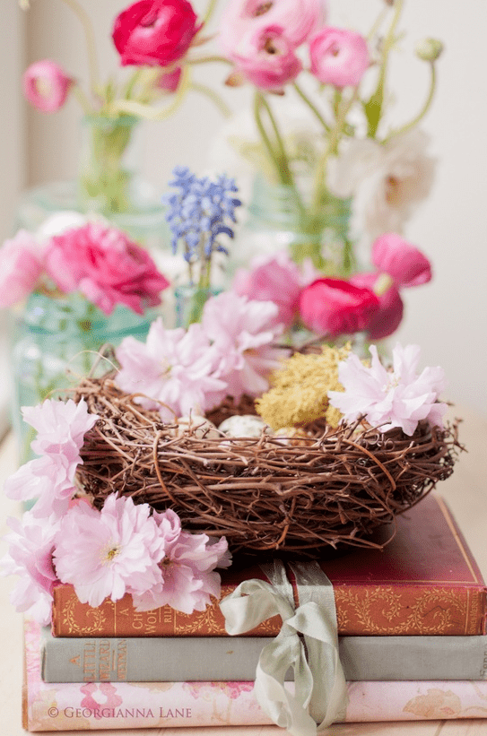 a nest with pink blooms and faux eggs is a cool idea of an Easter centerpiece for a rustic tablescape