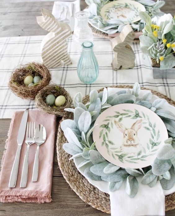 a neutral farmhouse tablescape with printed textiles, a woven placemat, faux greenery and succulents, nests with eggs for decor