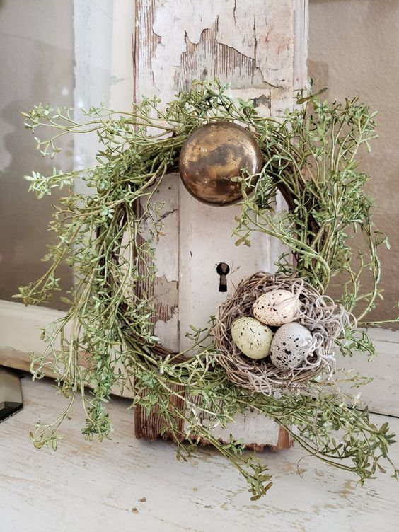 a rustic Easter wreath of vine and greenery plsu a fake nest with eggs is a cool decoration for Easter and spring