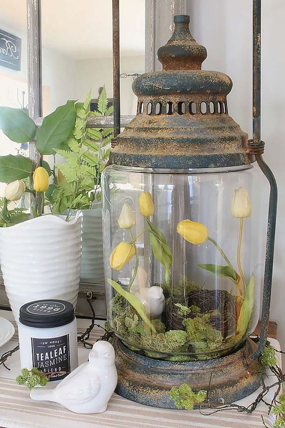 a shabby chic spring terrarium with moss, a faux nest, a bird and yellow tulips is a cool decoration to make