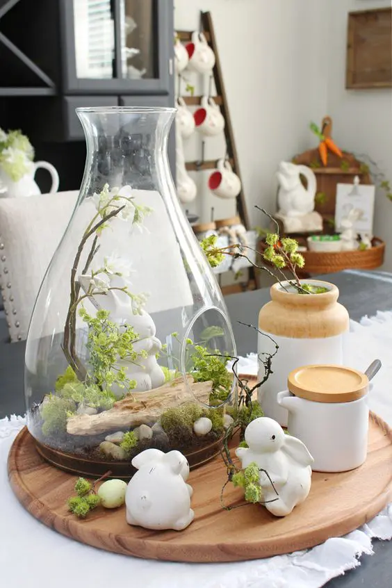 a spring jar terrarium with moss, pebbles, driftwood and a bunny plus bunny figurines around to add a cute touch
