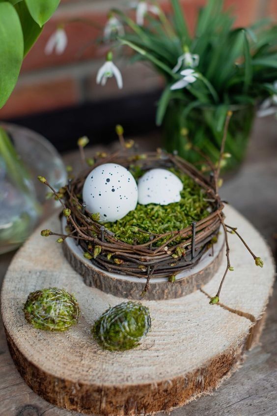 an Easter decoration of a nest with moss and speckled egs placed on a tree slice is cool and cozy