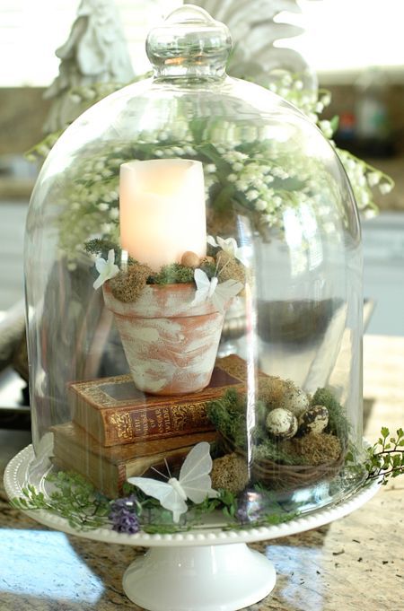 an Easter terrarium with greenery, moss, books, a canel and a faux nest with eggs is easy to make yourself