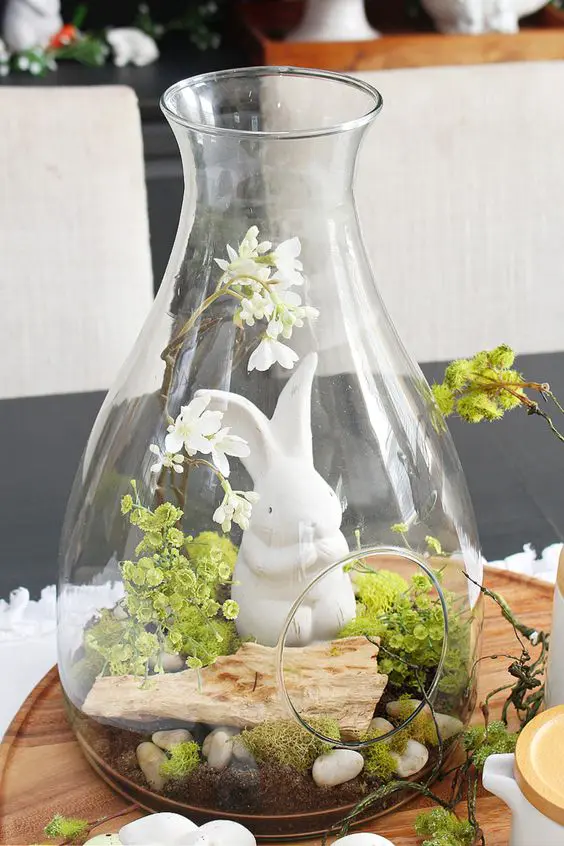 an Easter terrarium with greenery, moss, pebbles, wood and a little bunny is a cool idea for spring decor