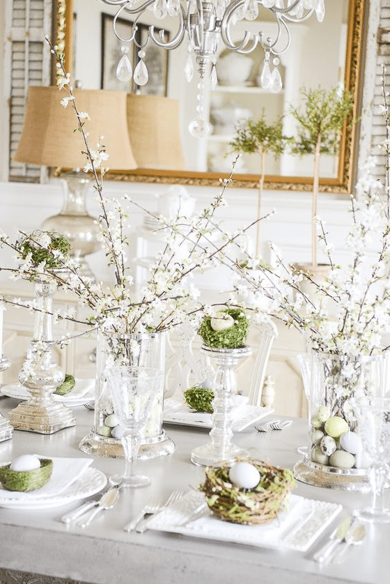 an elegant Easter brunch tablescape with blooming branches, nests with eggs, elegant candleholders with eggs