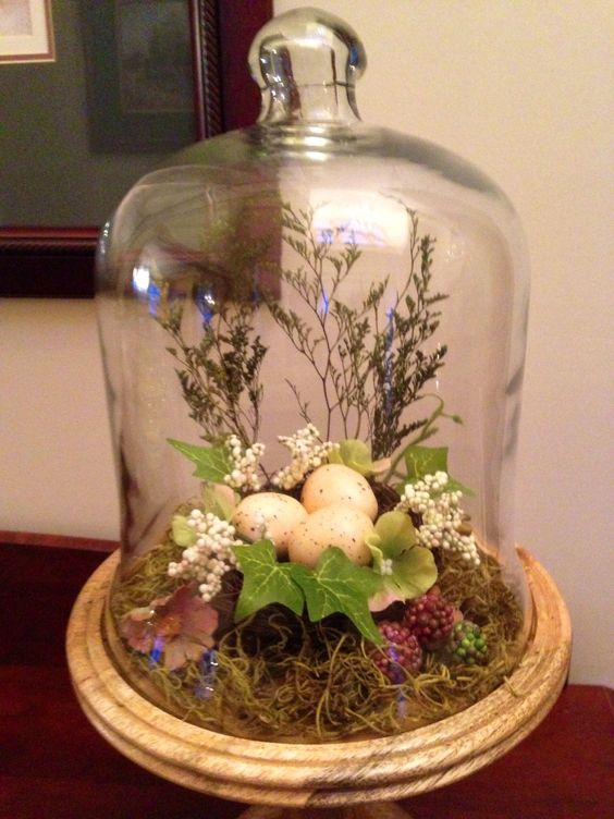 an eye-catchy spring to Easter terrarium with moss, leaves, berries, branches and a faux nest with eggs