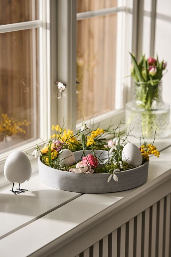 modern Easter decor with a concrete bowl with greenery and fresh spring blooms plus some faux eggs is cool