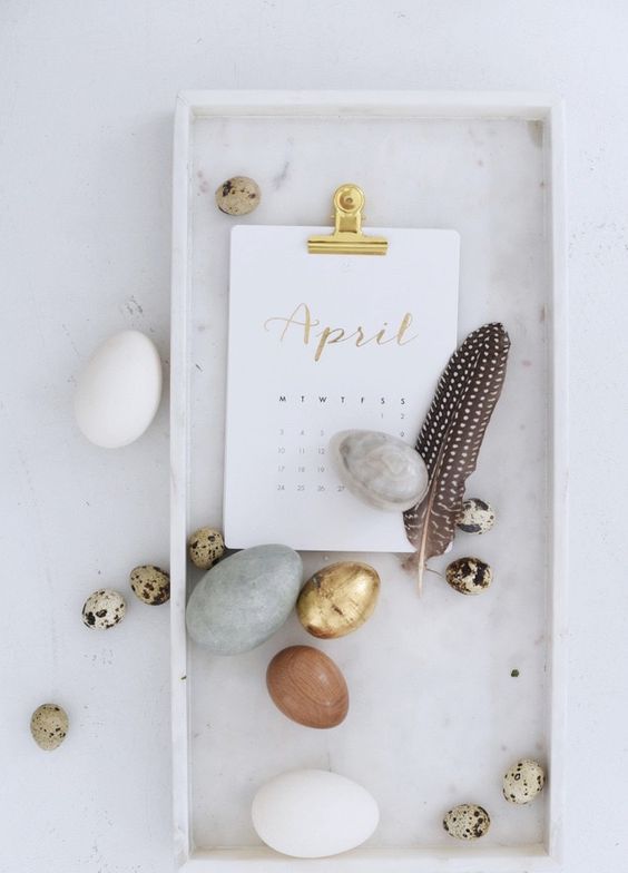 modern Easter decor with a stone tray, neutral stone eggs, speckled and gilded ones and a single feather is very chic