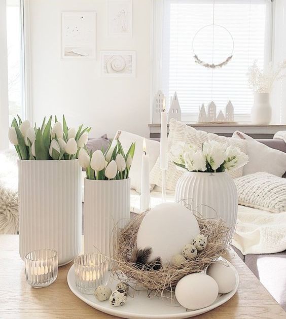 modern white Easter decor with tulips and roses, a nest with an oversized egg and some more eggs and candles
