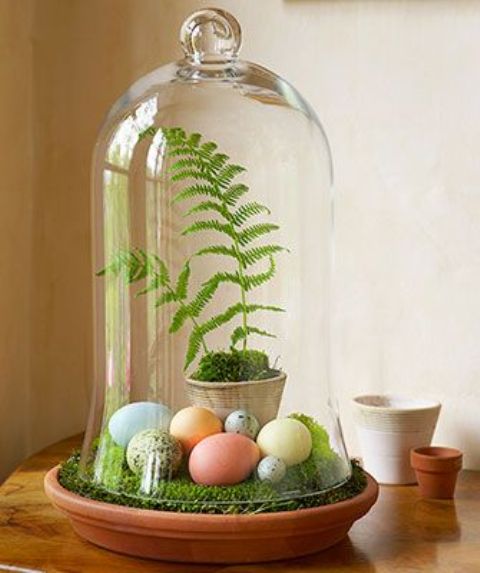 a cloche with moss, pastel dyed eggs and ferns