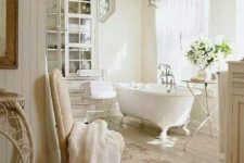 02 tranquil all-white bathroom with a glass cabinet and a gorgeous chandelier over the tub