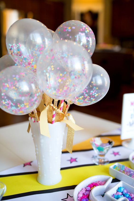 a white vase with glitter gold paper and sheer balloons with colorful confetti inside