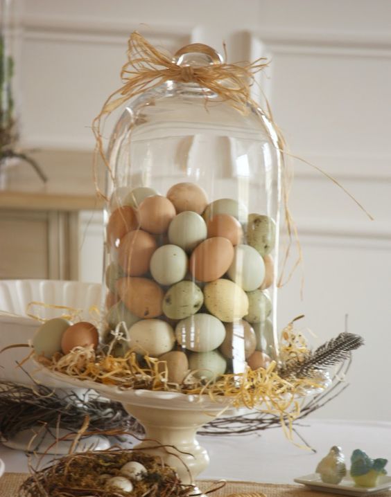 a cake stand with straw and naturally dyed eggs in a ball jar