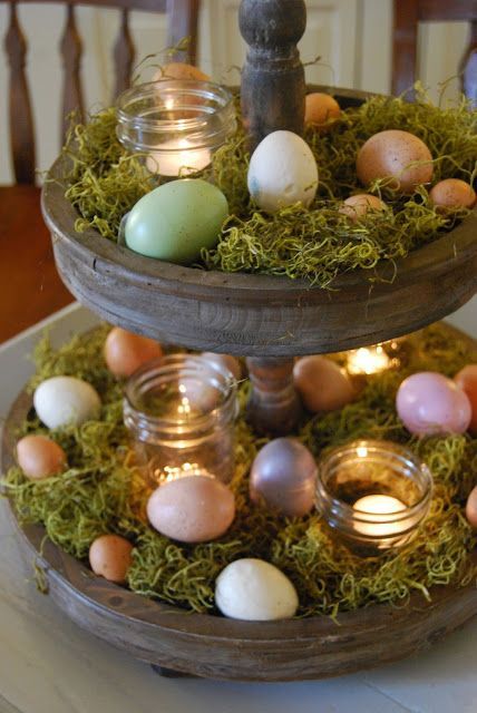 a vintage wooden cupcake stand with moss, candles and pastel eggs