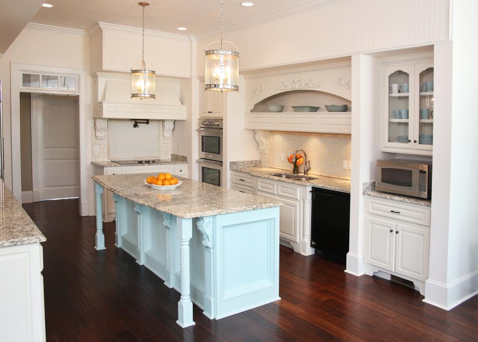 A white kitchen with a mint kitchen island and grey marble countertops