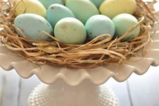 06 a cake stand with straw and pastel eggs can double as a centerpiece