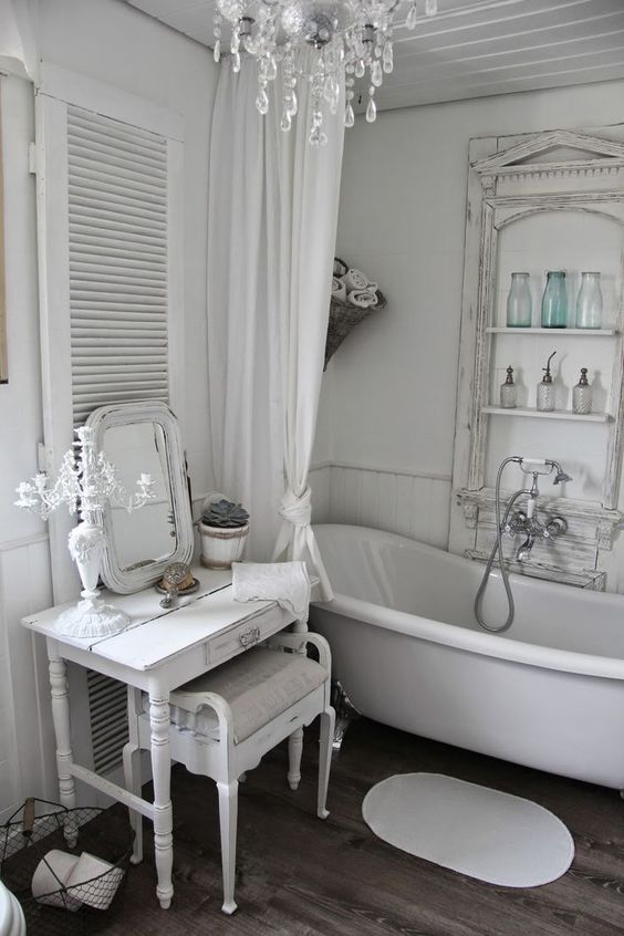 a small whitewashed vanity table and an upholstered stool for a feminine bathroom