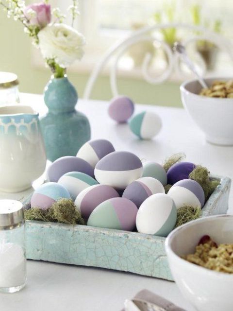 a pale blue wooden tray with moss and colored modern eggs