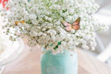 12 a mint-colored mason jar with baby’s breath and faux butterflies