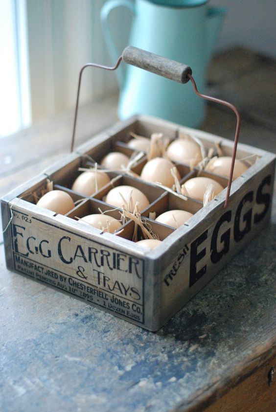 the wooden egg crate features a vintage style company logo, wire handle, and one dozen plastic eggs nestled in straw
