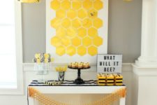 13 yellow lanterns with bees attached over the dessert table
