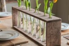 16 a frame of repurposed pallets with bottles and single tulips in each